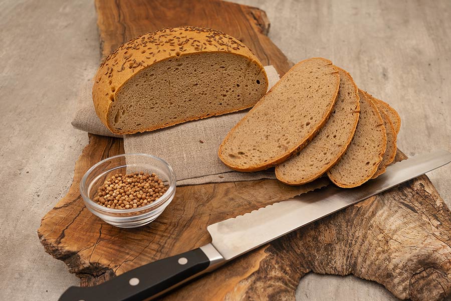 Gewürzbrot hausg`macht im PurNatur Kempten mit aufgeschnittenen Scheiben und Kümmel auf Holzbrett